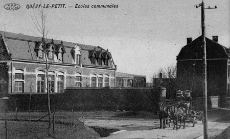 Un chariot transportant vraisemblablement des tonneaux de bière pose devant  l’école